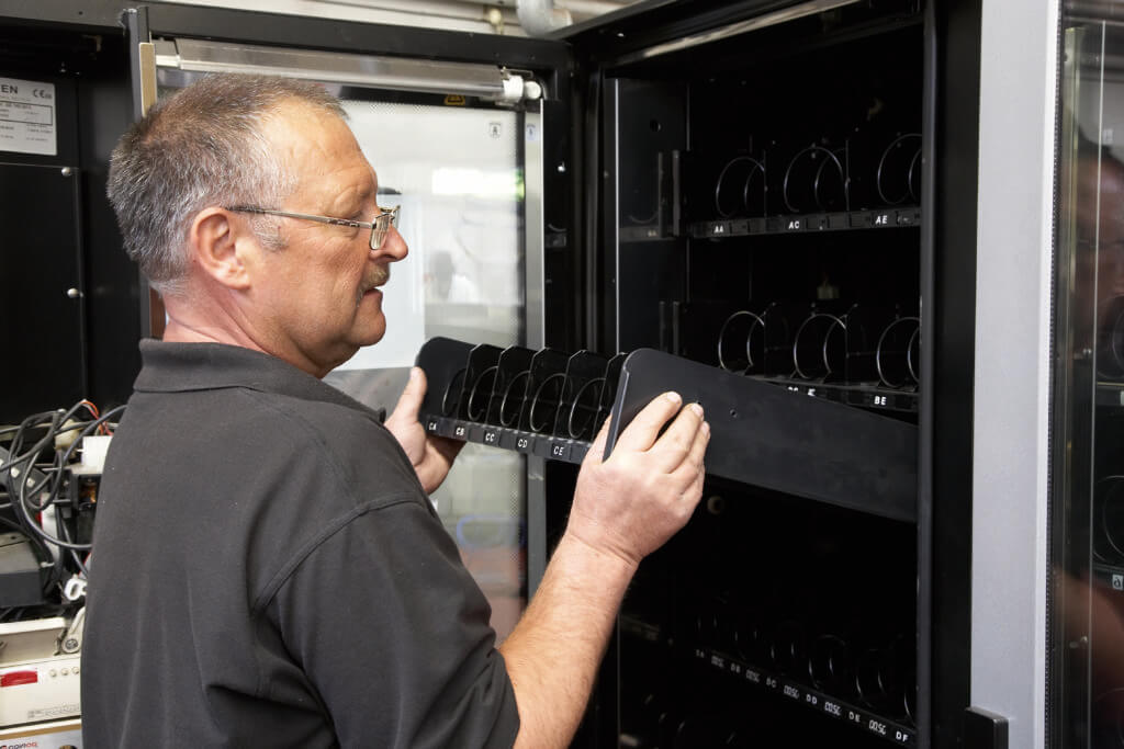 Man fitting coils to the inside of Vending machine